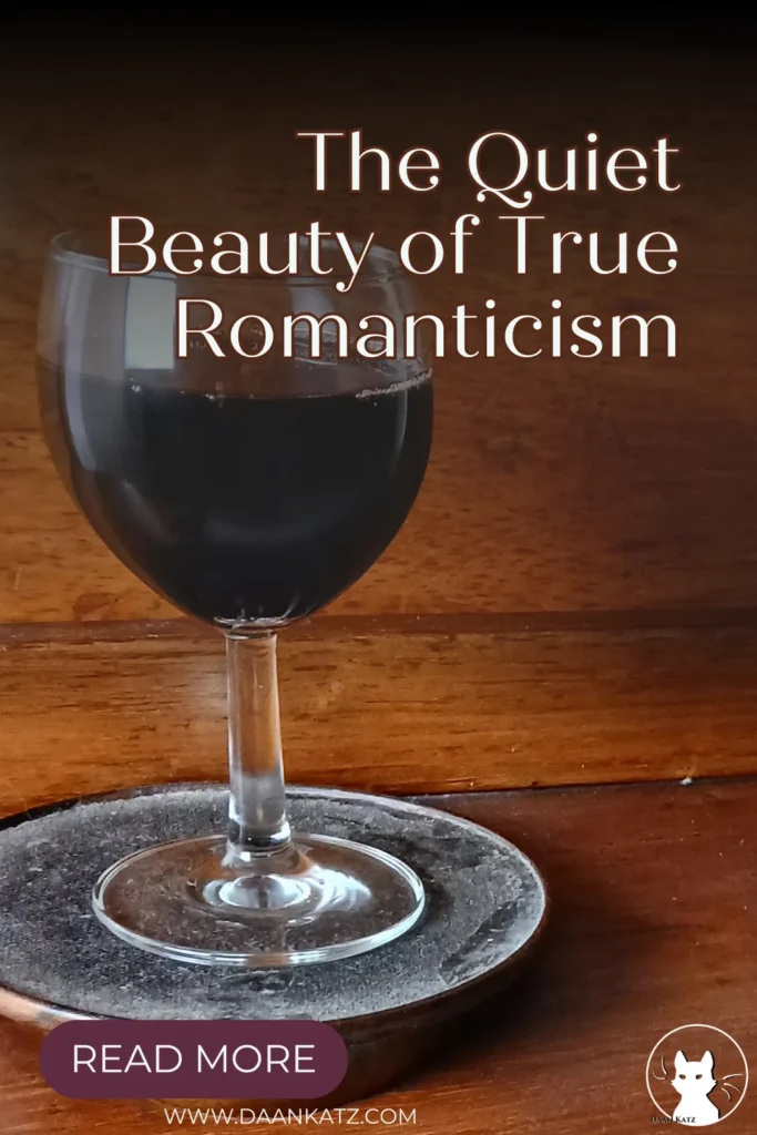 A glass of wine stands on a dusty black standard on a wooden surface. Text overlay reads: The beauty of true romanticism