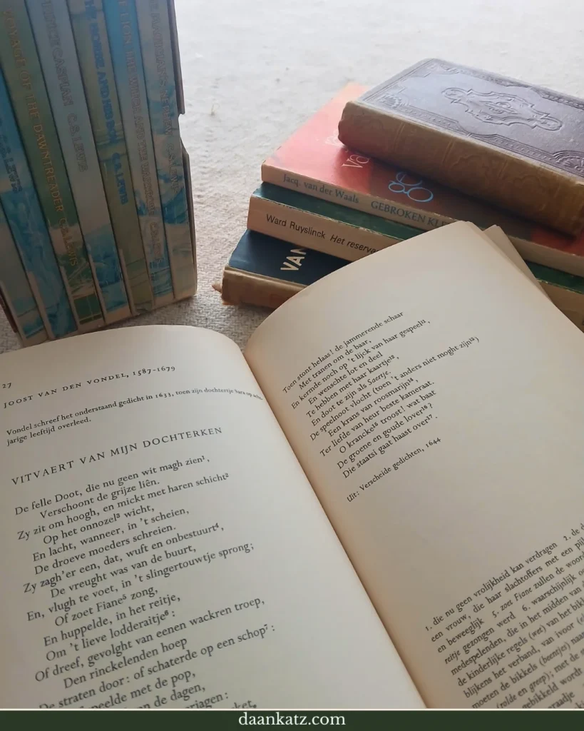 An open book with Dutch text lies on a table surrounded by stacked and upright books, including classic literature, Dutch literature, and poetry, as well as enchanting fairy tales.